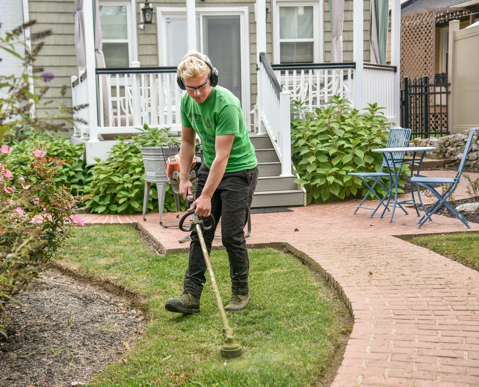 String trimmer running a clean edge between turf and concrete sidewalk.